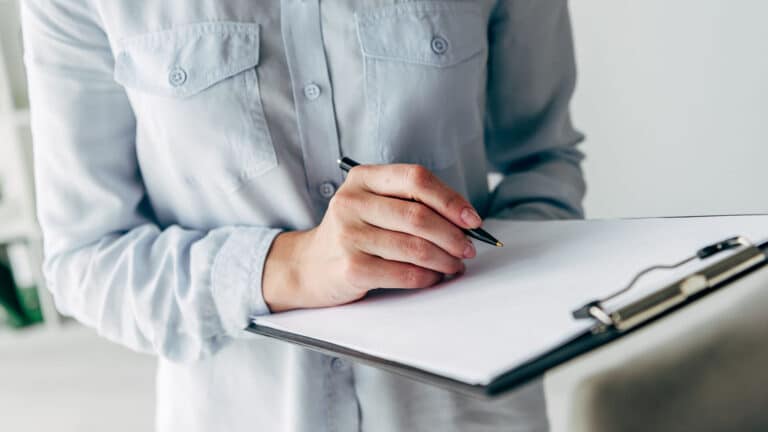 person writing in a clipboard