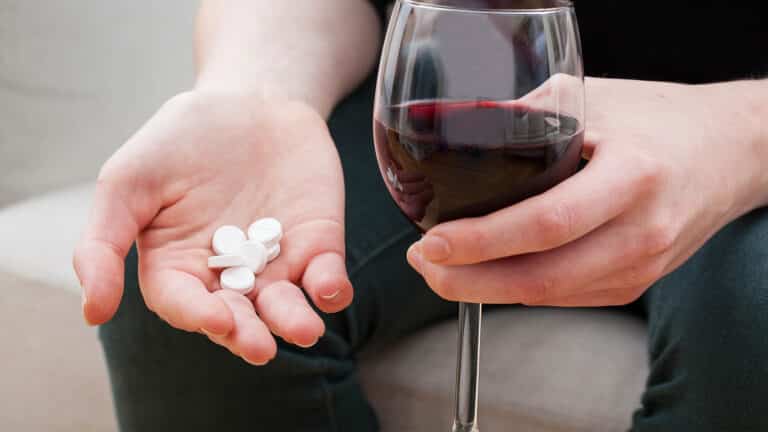 Woman taking tablet and alcohol