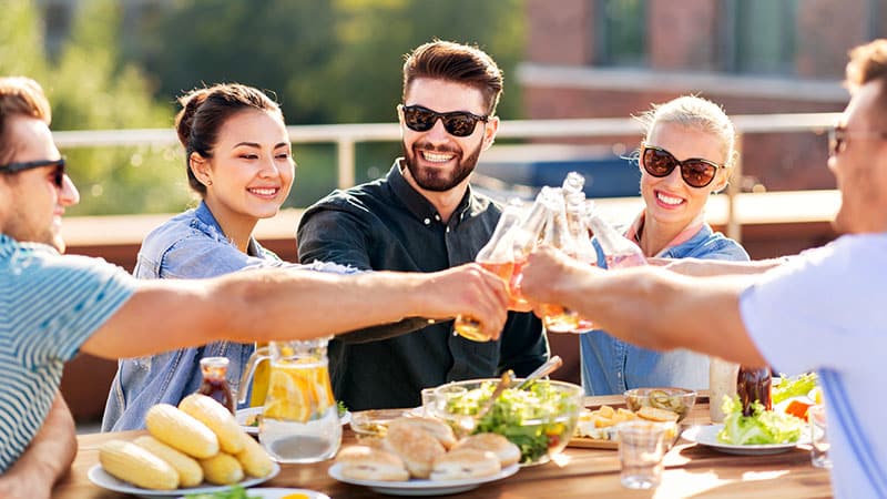Happy friends toasting drinks at rooftop party