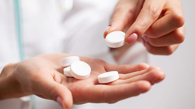 Doctor close up holding white pills for weight loss