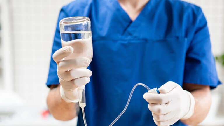 Doctor in blue uniform holding drip iv and infusion pump