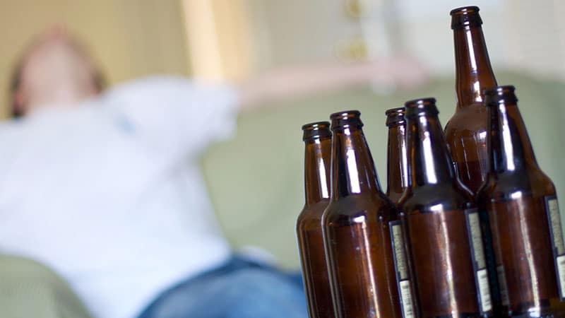 Man passed out on couch with empty beer bottles