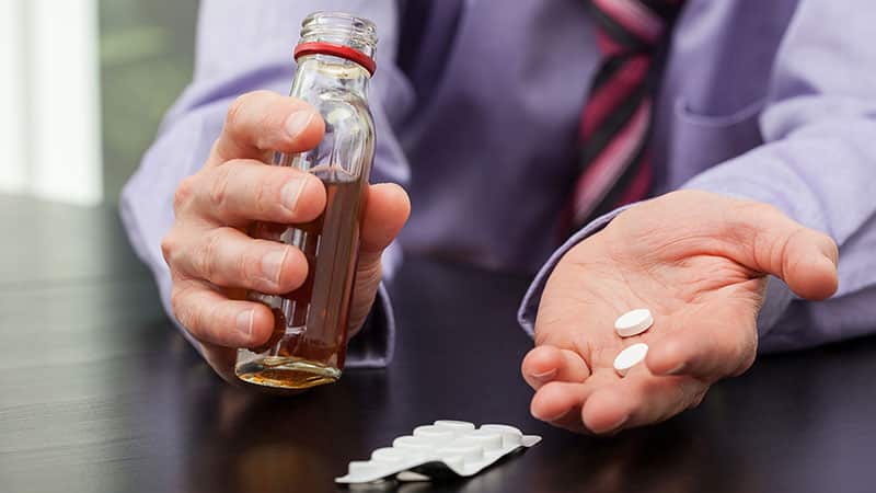 man holding medication and alcohol