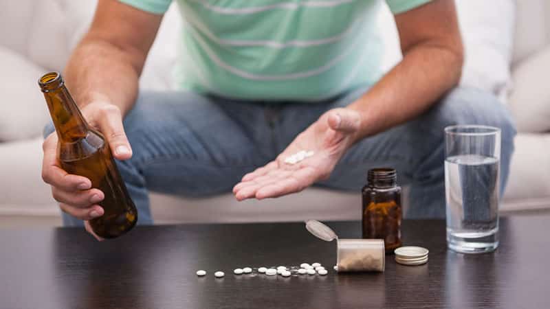 man mixing his beer with medication