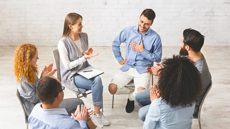 Happy people clapping at support group therapy