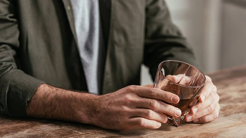 man holding whiskey glass at table