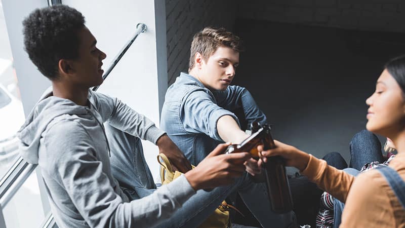 Happy and smiling teenagers sitting on stairs and clinking