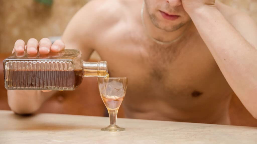 alcoholic man table pours alcohol glass