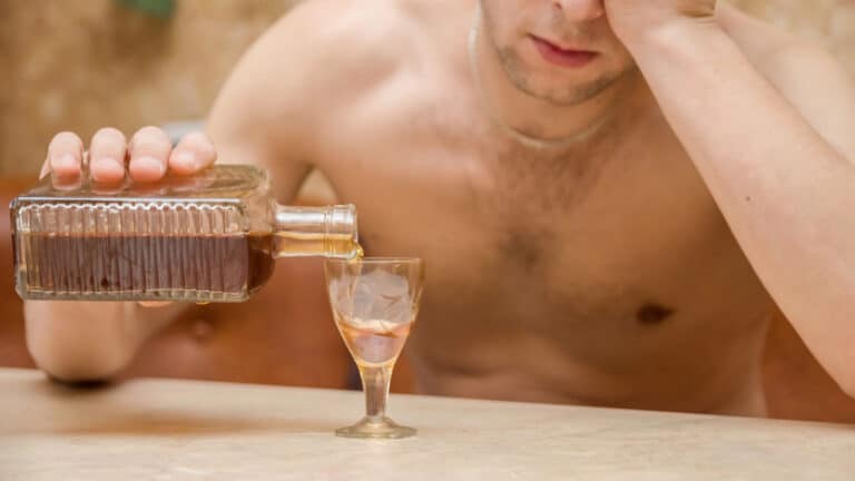 alcoholic man table pours alcohol glass