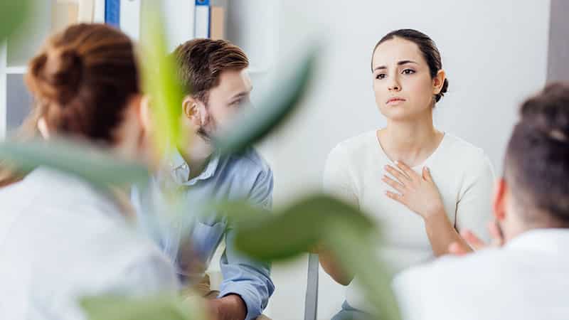 woman gesturing group therapy meeting
