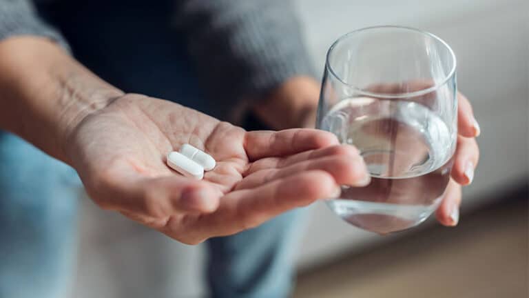 woman taking medication while sitting couch