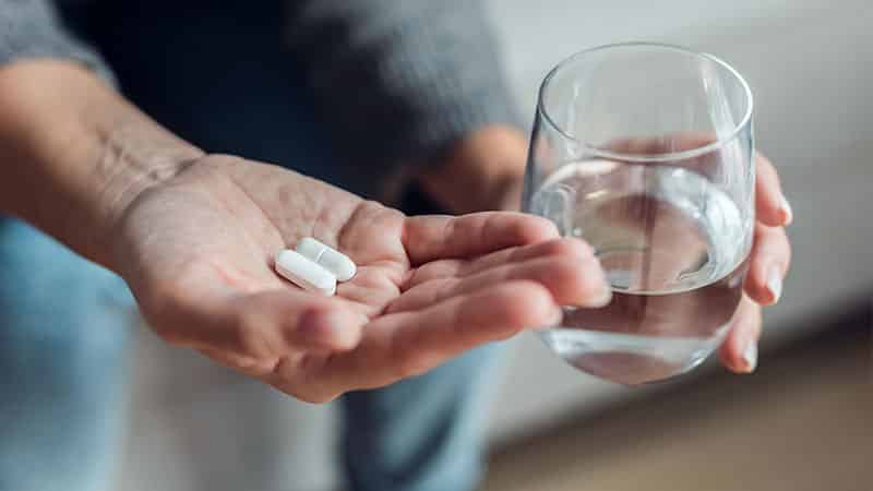 woman taking medication while sitting couch