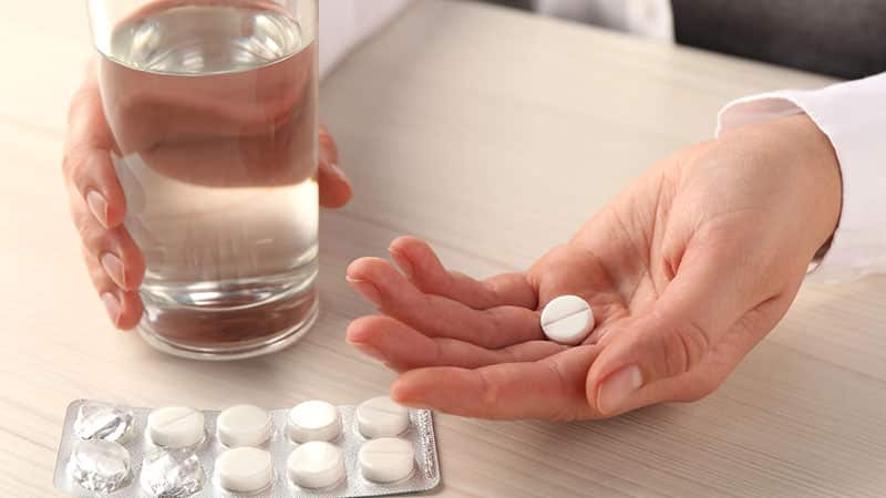 Woman with pills and glass of water