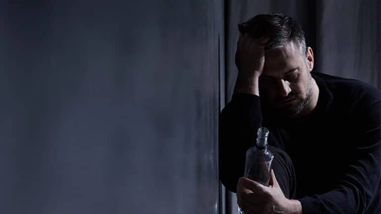 male person staring at an alcohol bottle