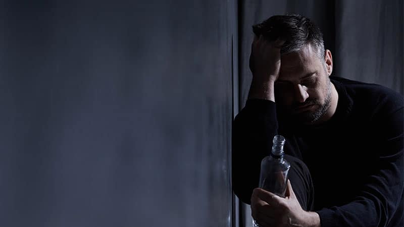 male person staring at an alcohol bottle