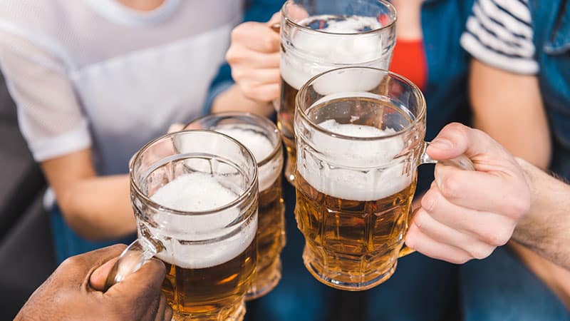 partial view of young friends holding glasses of beer